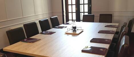 A conference room with a long table, chairs, and a bottle of water.