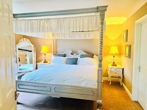 A four-poster bed with a canopy, two bedside tables with lamps, a mirror, and a door to the left. - Wrexham Llyndir Hotel by Belvilla (Wrexham)