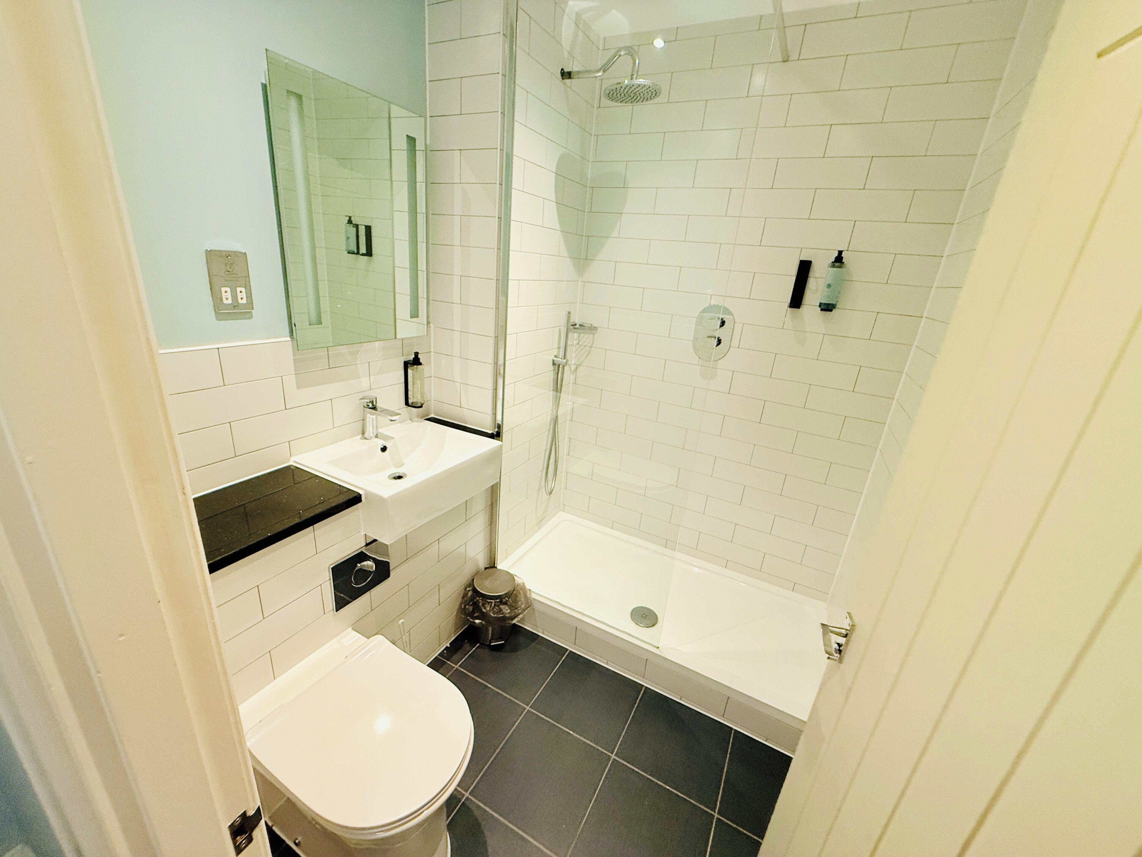 A bathroom with a white sink, mirror, and a shower with a glass door.