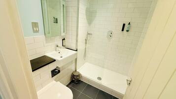A bathroom with a white sink, mirror, and a shower with a glass door.