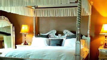 A four-poster bed with a canopy, two bedside lamps, and a mirror on the left.