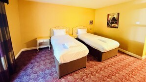 Una habitación de hotel con dos camas, una mesita de noche y una alfombra estampada.