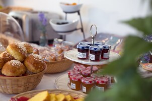 Una mesa con diversos alimentos, incluyendo pan, pasteles y frascos de mermelada.