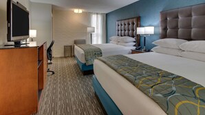 A hotel room with a bed, a desk, a television, and a lamp.