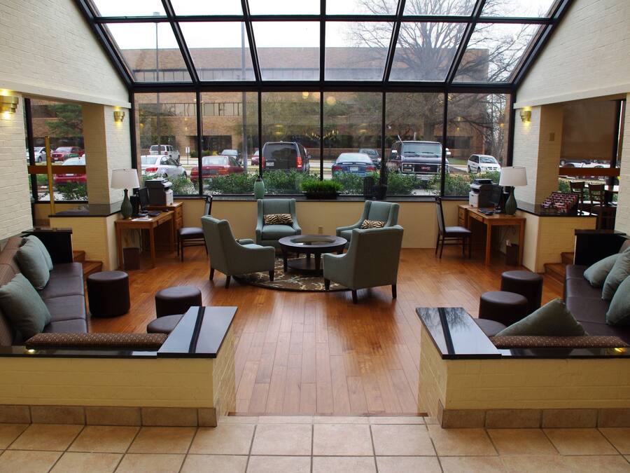 A spacious lobby with a high ceiling, large windows, and a central seating area with sofas and chairs.