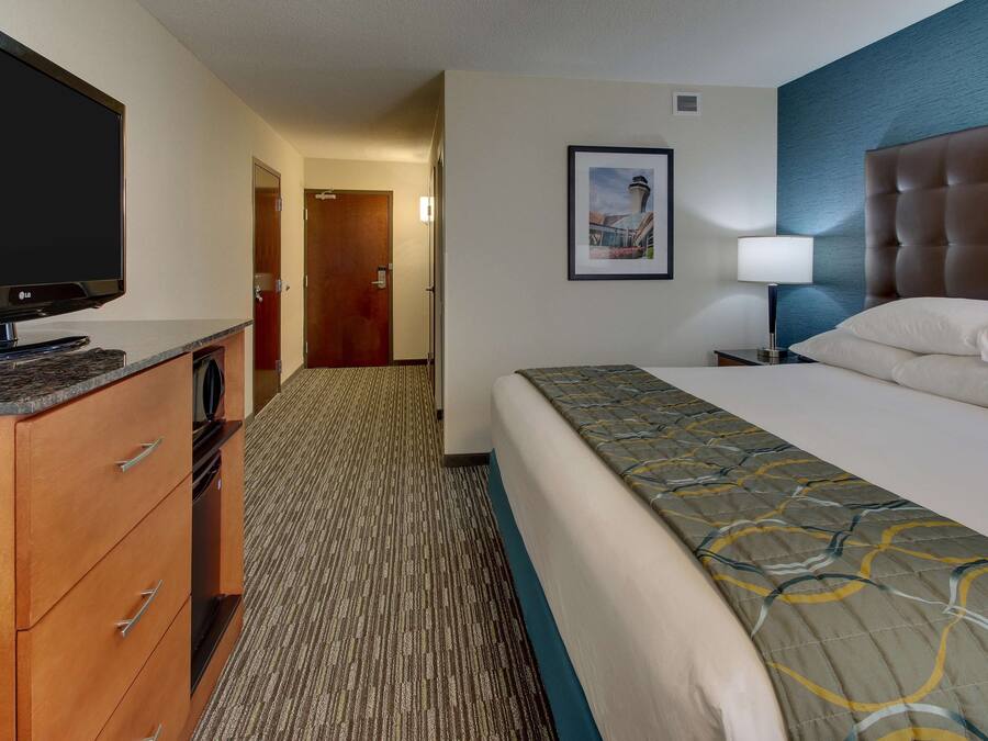 A hotel room with a bed, a television, a dresser, and a framed picture on the wall.
