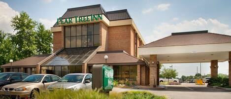 A Pear Tree Inn with a brick facade, large windows, and a covered parking area.