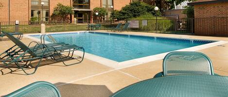 A swimming pool with lounge chairs and a building in the background.