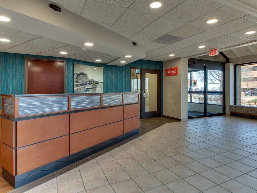 A reception area with a wooden reception desk, a blue wall, and a tiled floor.
