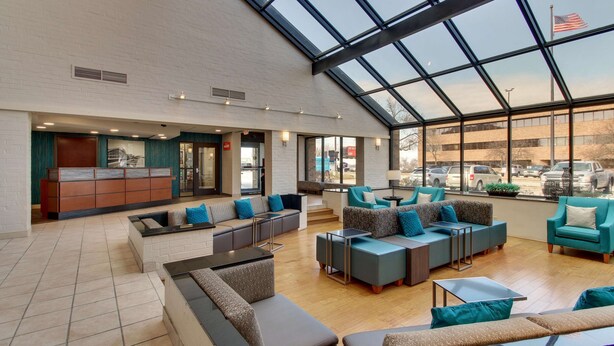 A spacious lobby with modern seating, a reception desk, and large windows offering views of the parking area.
