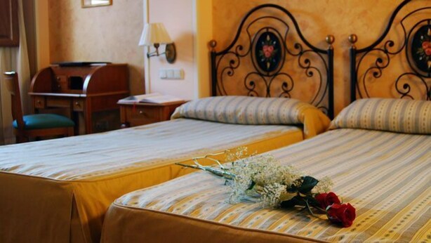 Une chambre d’hôtel avec deux lits, un bureau et une lampe.