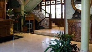 Un vestíbulo con una escalera, un letrero que dice "CAFETERIA" y un espejo grande a la derecha.