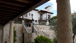 Un patio con columnas de piedra, una escalera y un edificio con tejado de baldosas.