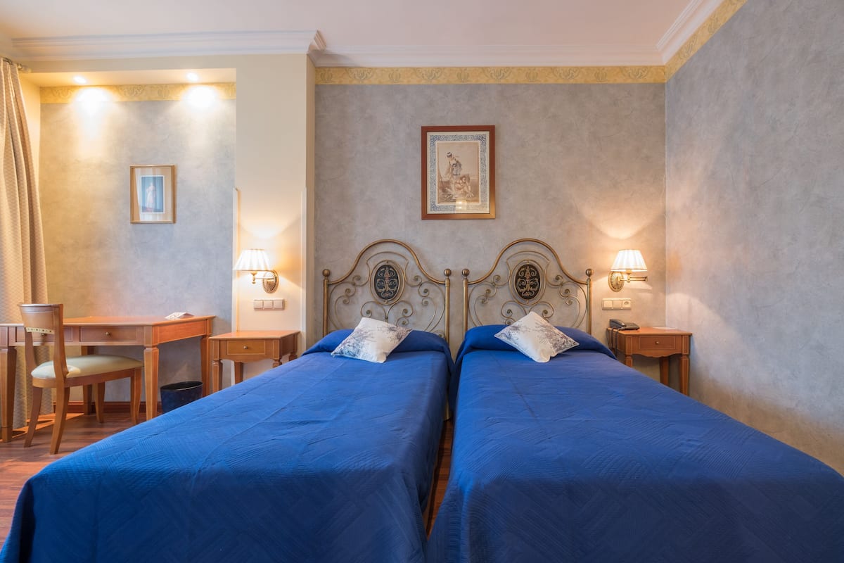 Een hotelkamer met twee bedden, een bureau en een stoel.