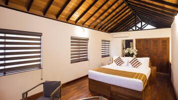 A bedroom with a wooden ceiling, a bed with white bedding, wooden shutters, and a chair.