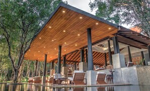 Un espacio al aire libre cubierto con suelo de madera y asientos, rodeado de árboles.