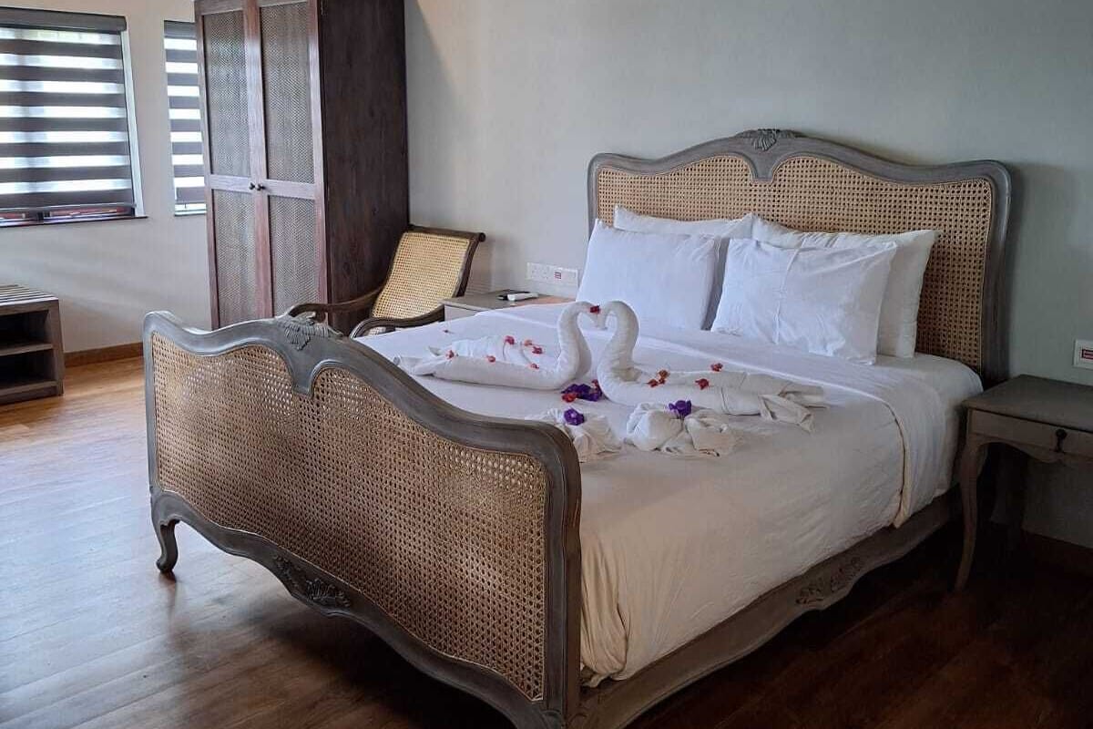 Een ruime slaapkamer met een groot bed, houten vloer en een kledingkast.