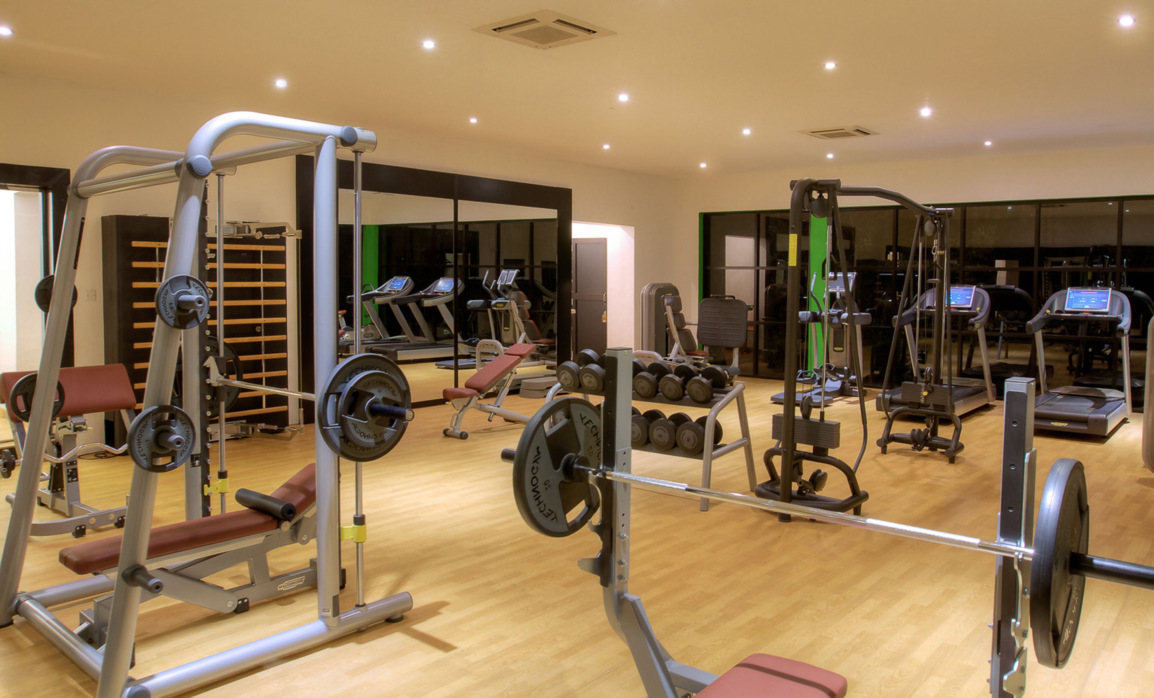 A gym with various exercise equipment, including weight machines, treadmills, and dumbbells.