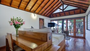 Una mesa de comedor de madera con sillas, un jarrón de flores y una cama con vistas al exterior.