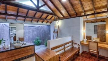 A bathroom with a wooden vanity, a large mirror, a bench, and a wooden ceiling.