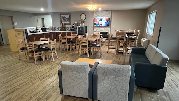 A spacious living area with a kitchen, dining area, and seating arrangements including a sofa and chairs. - Days Inn & Suites by Wyndham Williamsburg IA North (Williamsburg)