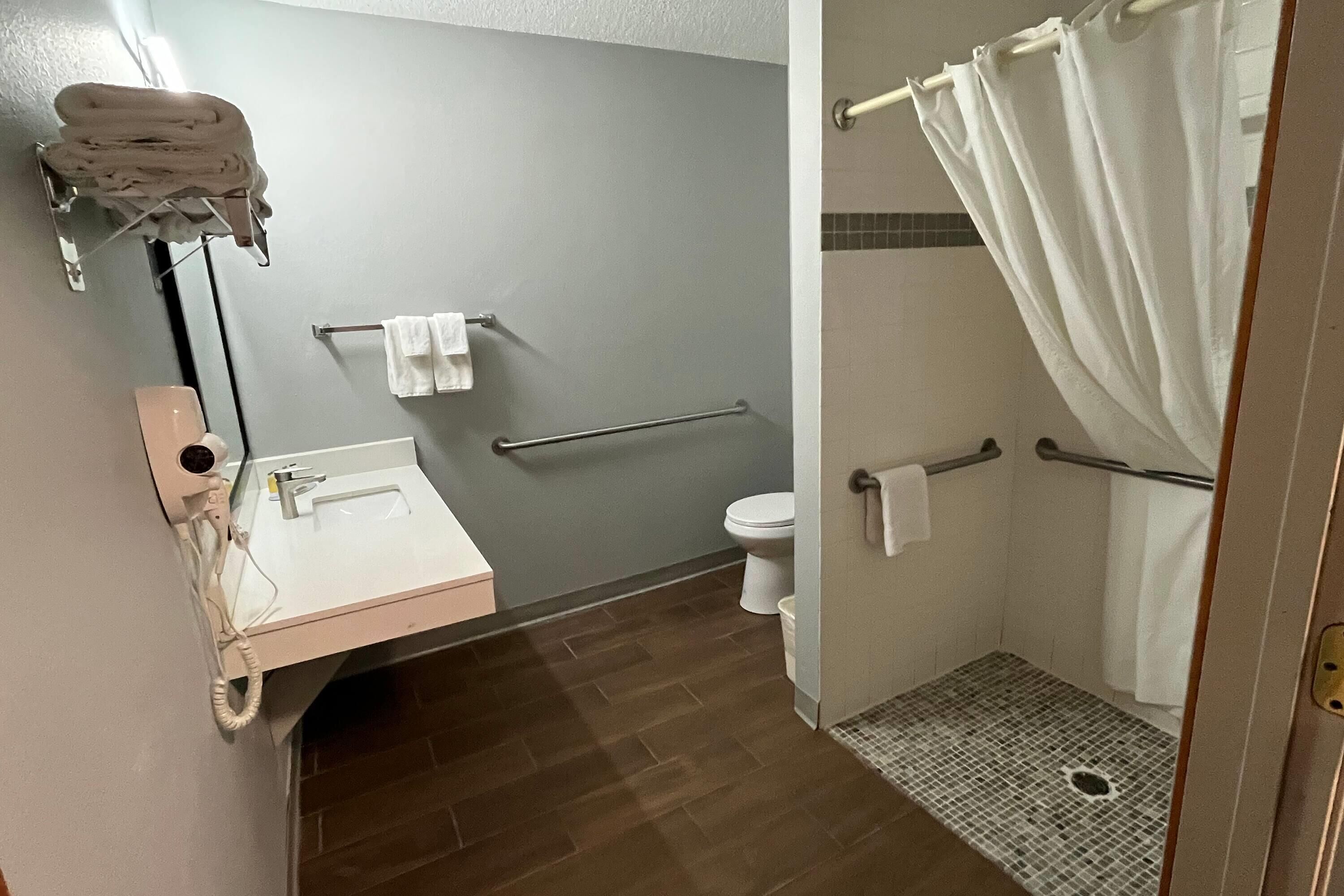 A bathroom with a sink, toilet, and shower area.