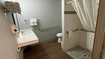 A bathroom with a sink, toilet, and shower area.