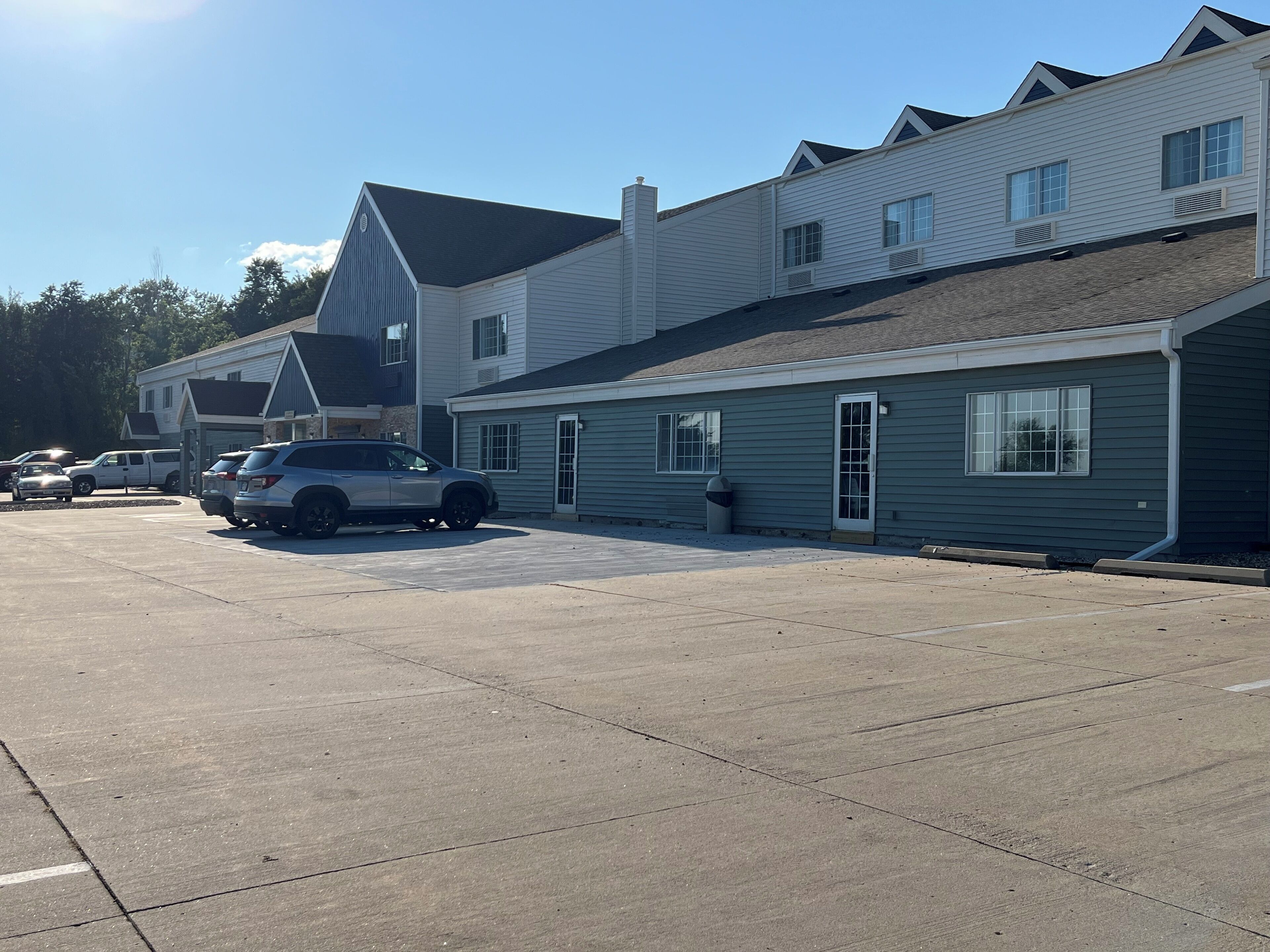 A parking lot with several vehicles and a row of buildings with a simple, functional design.