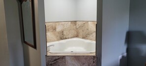 A bathroom with a freestanding bathtub, marble tiles, and a framed mirror. - Days Inn & Suites by Wyndham Williamsburg IA North (Williamsburg)
