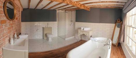 A bathroom with a freestanding bathtub, a shower, and a vanity with a mirror.