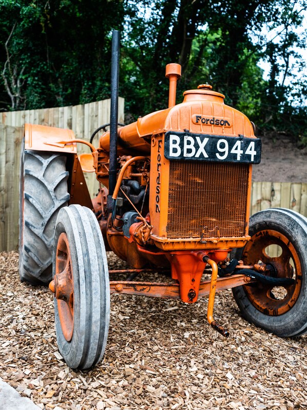 Un tractor naranja antiguo con la matrícula BBX 944, estacionado sobre una capa de astillas de madera.