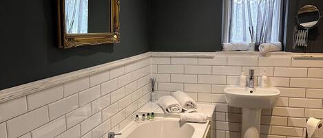A modern bathroom with a large bathtub, a sink, and a mirror.