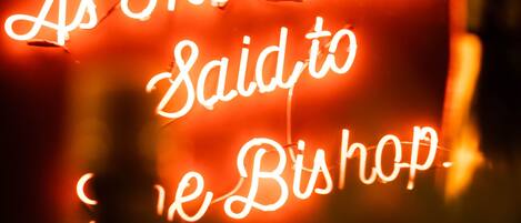 A neon sign with the text "As The Actress Said to The Bishop."