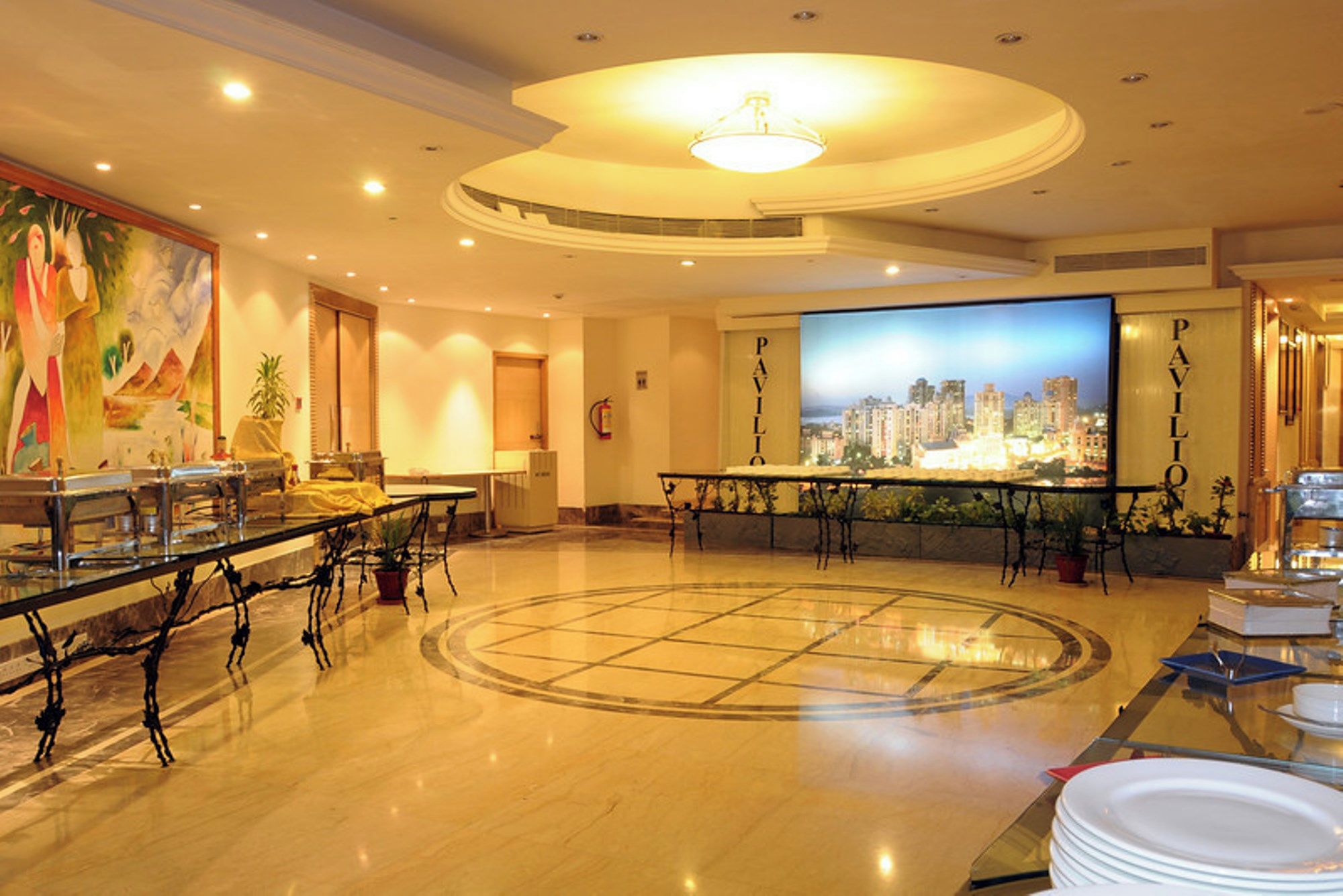 A hotel lobby with a central seating area, a large cityscape mural, and a reception desk.