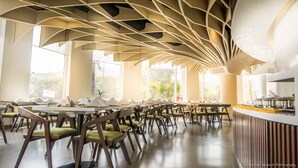 Un comedor moderno con techos altos y luz natural gracias a amplias ventanas.