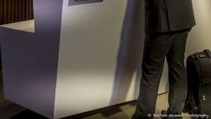 Mostrador de recepción con un letrero que dice "RECEPTION" y un hombre con traje de pie.