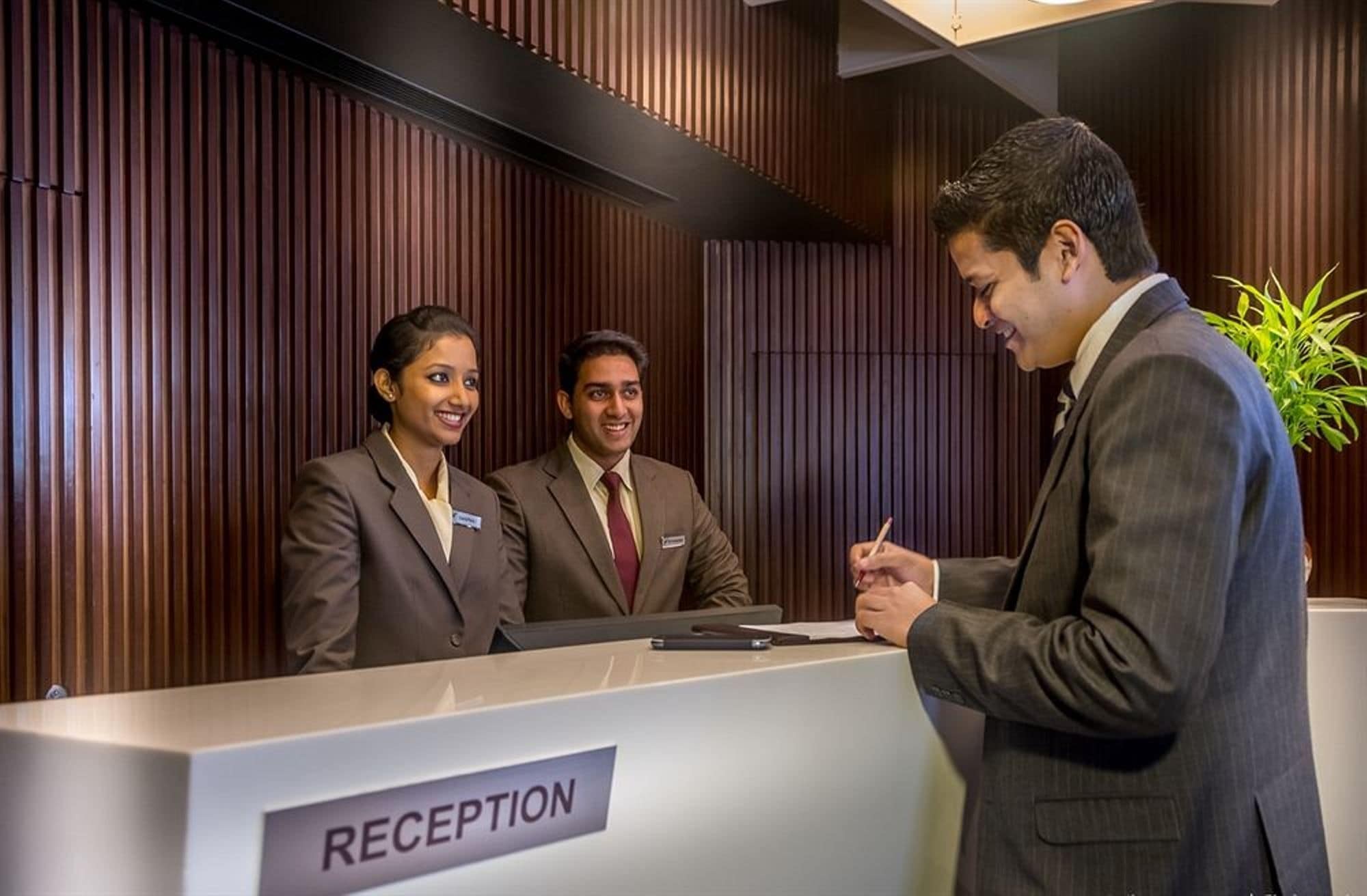 A reception desk with a sign labeled 'RECEPTION' and a plant to the right.