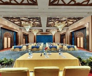 A conference room with multiple round tables, each with chairs, and a large chandelier. - Rodas An Ecotel (Mumbai)