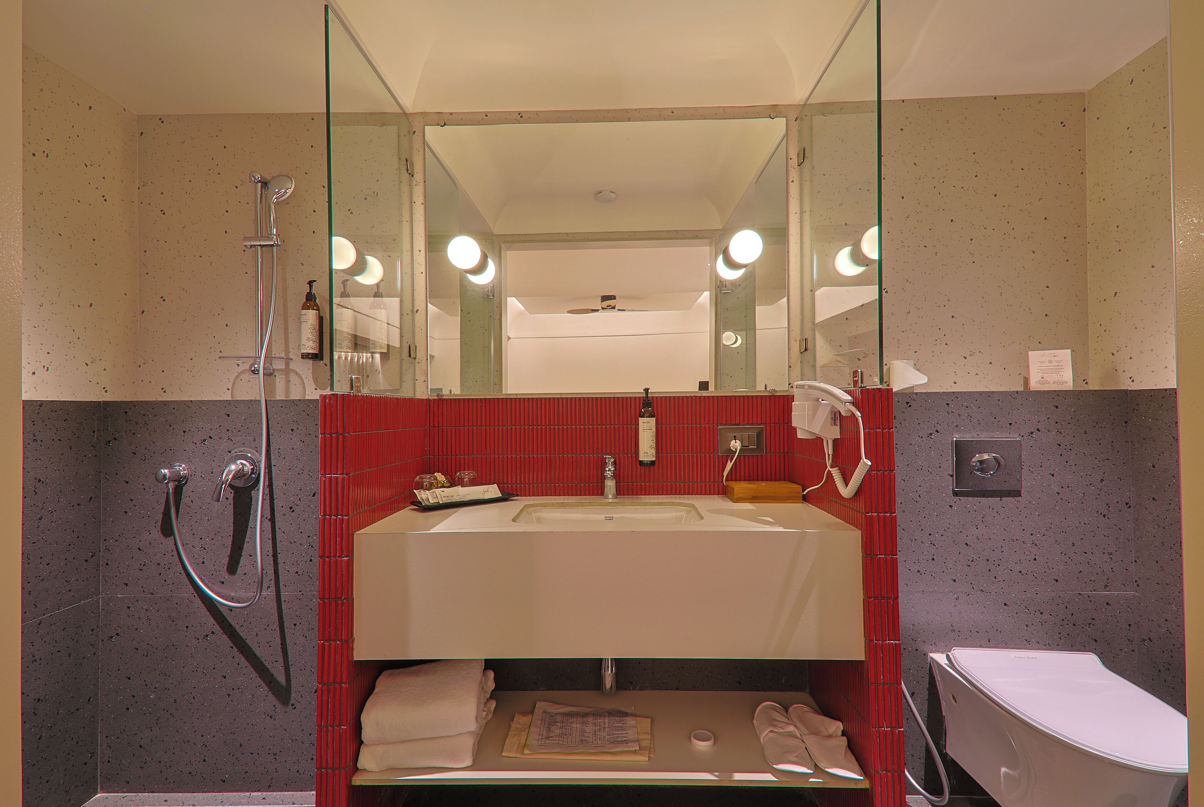 Een badkamer met een glazen douchecabine, een wastafel en een toilet.