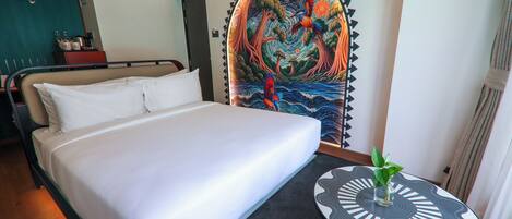 Una habitación de hotel con una cama, un mural en la pared y una mesita con una planta.