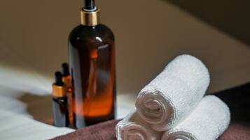 Un área de spa bien organizada con una toalla marrón, una botella de loción y un folleto sobre una cama.