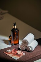 Un área de spa bien organizada con una toalla marrón, una botella de loción y un folleto sobre una cama.
