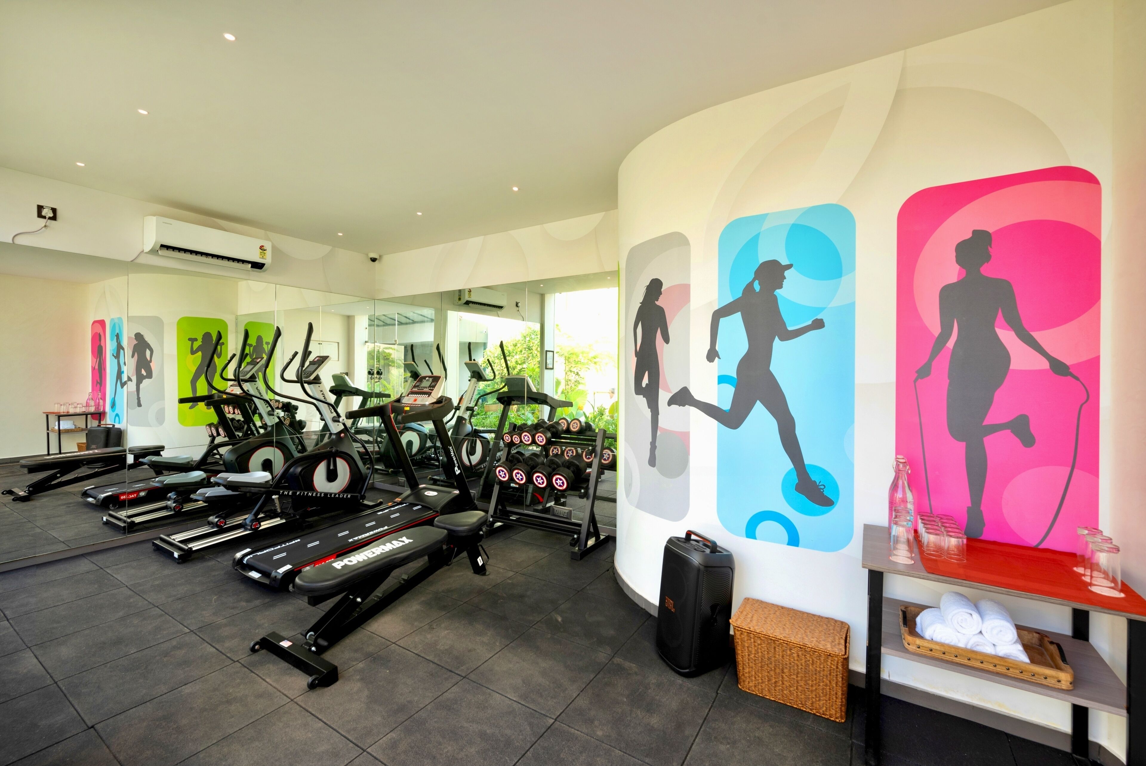 A gym with treadmills, stationary bikes, and dumbbells.