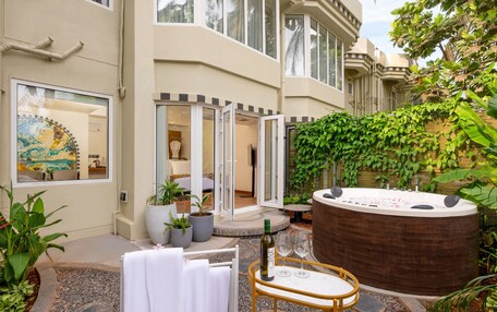 A spa area with a hot tub, a table with wine glasses, and a view of the interior through glass doors.