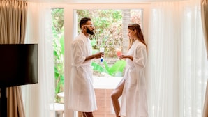 A room with a large window, a flat-screen TV, and a bed with a leopard print blanket. - The Orchid Passaros Goa - Adults Only Resort (Benaulim)