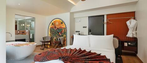 A modern hotel room with a large bed, a bathtub, a ceiling fan, a wardrobe, and a mirror.