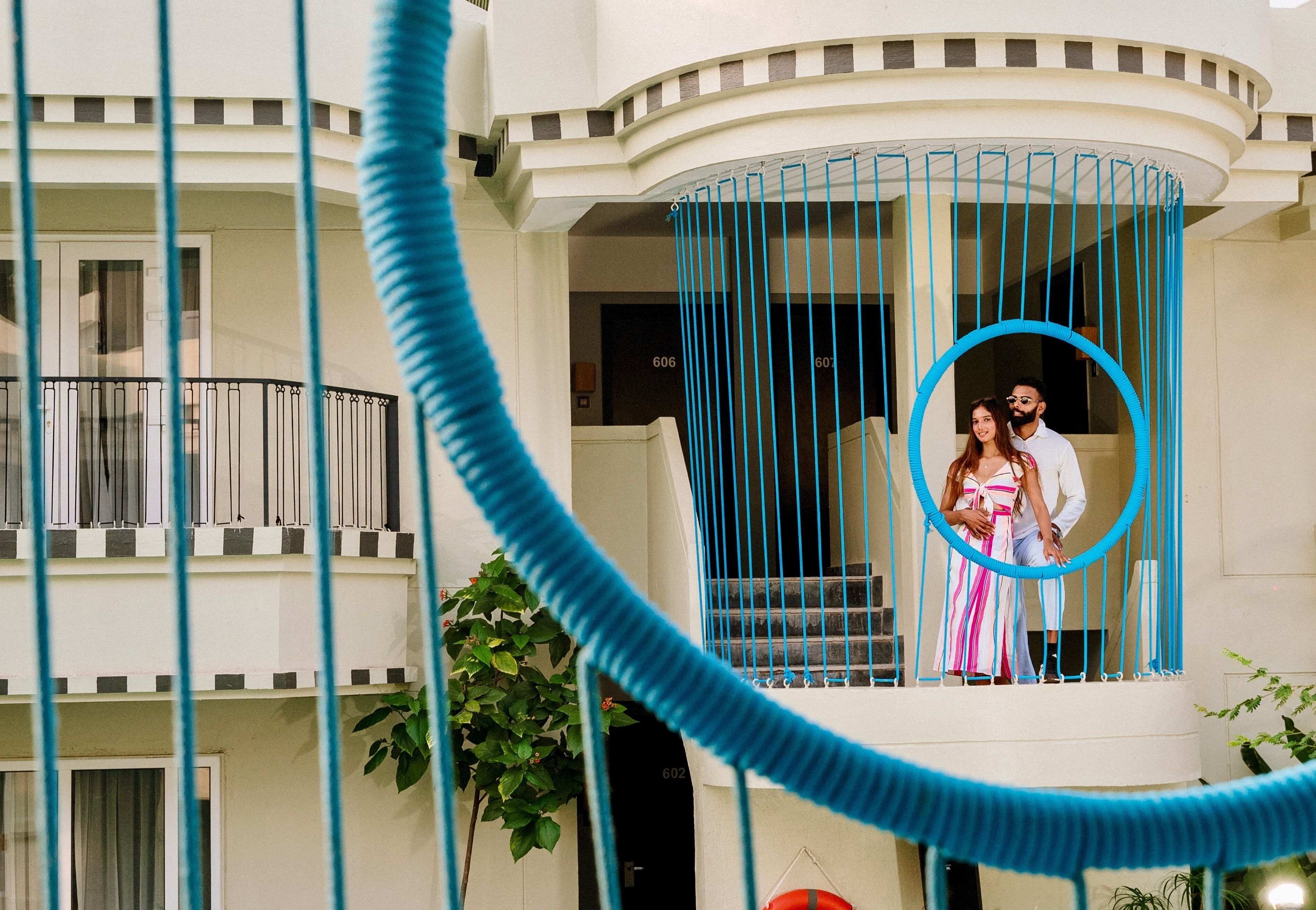 A couple standing on a balcony with a blue rope barrier.