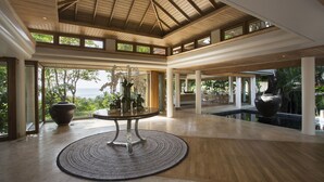 A spacious lobby with a high ceiling, large windows, and a central round table with a rug.