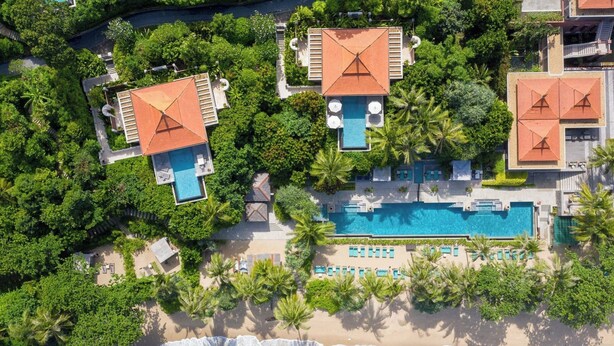 An aerial view of a resort with multiple buildings, a central swimming pool, and a beach. - Trisara Villas & Residences Phuket (Choeng Thale)