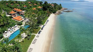 Vista aérea de un resort con playa, piscina y villas.